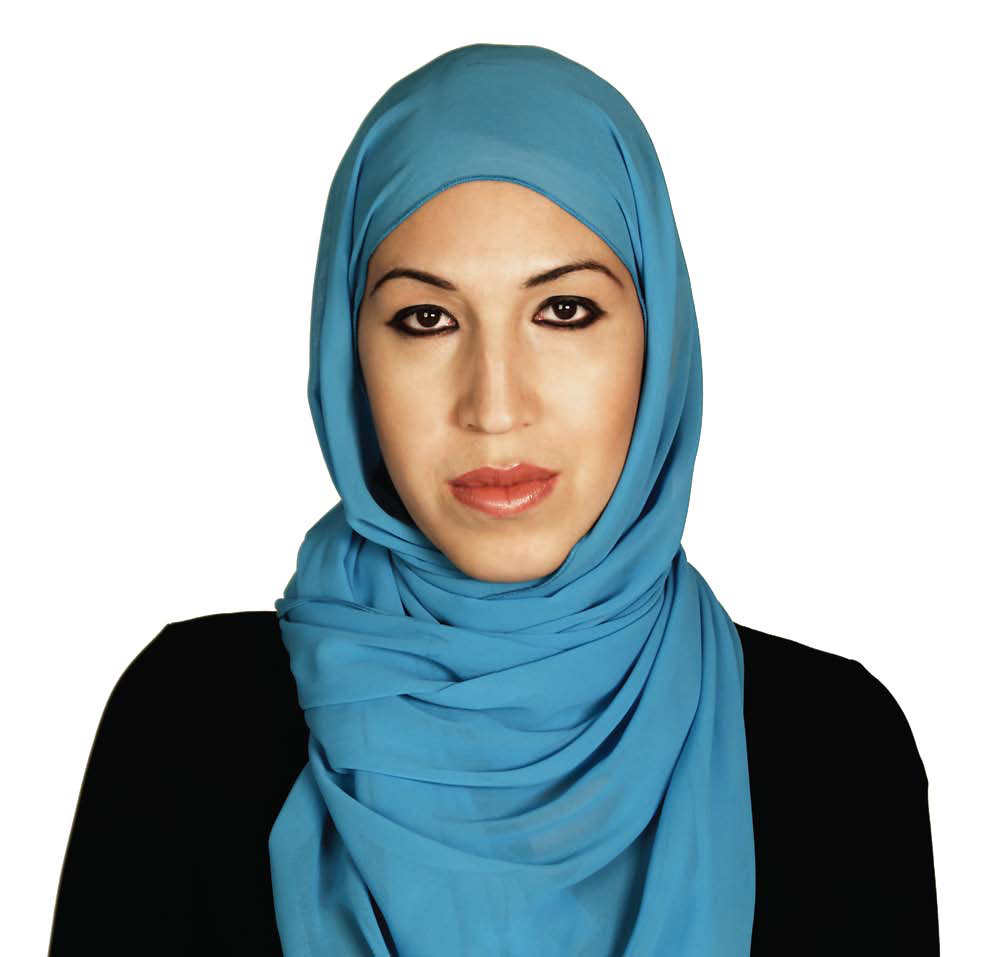 An image of a Brown woman wearing a blue hijab and a black long sleeved shirt, looking straight at camera. 